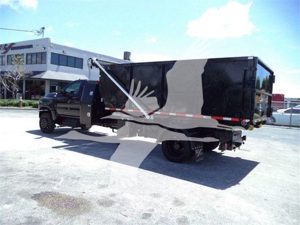Truck bed side view showing refuse truck with black cab and black dump body, side reflections and white/red reflective stripe.