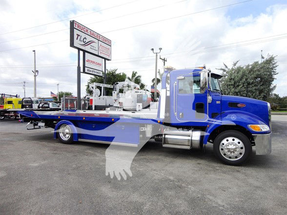 Blue Peterbilt 337 tow truck side view with a long wheelbase, flatbed, and chrome fuel tanks.