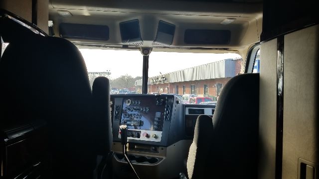 Cab cockpit of a Freightliner Coronado 132 truck showing the driver and passenger seats and dashboard with controls.