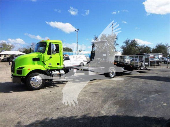 2025 Mack MD6 tow truck in bright green with a lowered bed on a dealership lot.