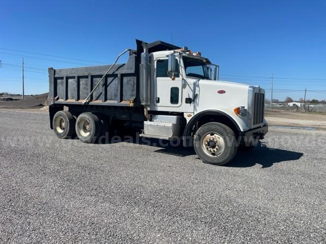 Peterbilt dump truck side view showing a white cab and black dump bed with dual rear axles and three-axle configuration.