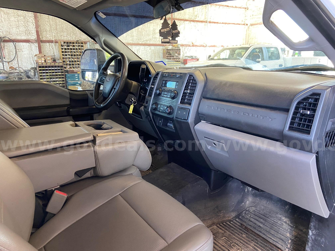 Ford F-450 Super Duty cab interior showing steering wheel, dashboard, center console, and front seats. Text 'SUPER DUTY' on the passenger side dash. Key in ignition. Stock and VIN visible in context.