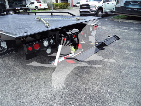 Truck bed of a 2023 Chevrolet Silverado 6500HD with hydraulic lift and rear ramps visible.