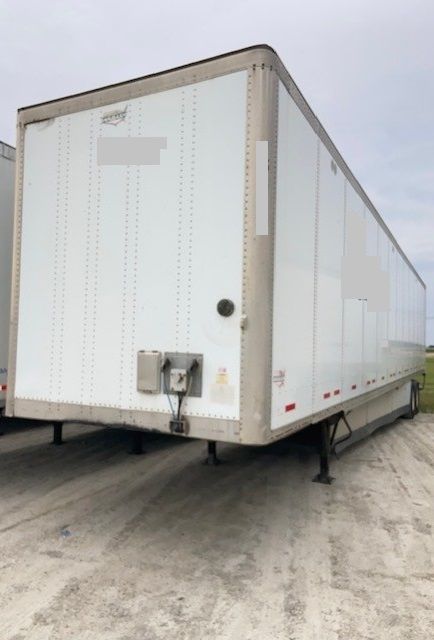 Trailer: white 2012 Wabash Duraplates semi-trailer with rear doors and landing gear, on a gravel surface.