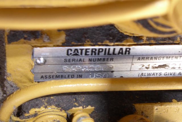 Close-up of a Caterpillar serial plate on a yellow piece of equipment showing SERIAL NUMBER and ASSEMBLED IN USA text.