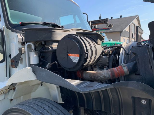 Truck engine bay of a 2006 International 4300 with visible air intake and hoses; front fender and wheel nearby.