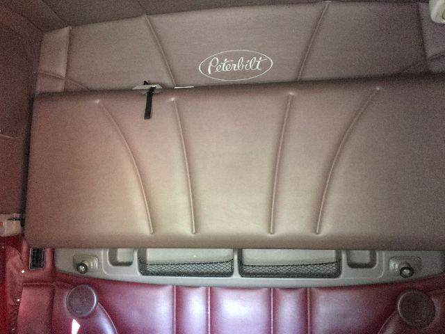 Peterbilt interior with brown leather sleeper seat back; visible Peterbilt logo on lower seat. The image shows a portion of the cab interior.