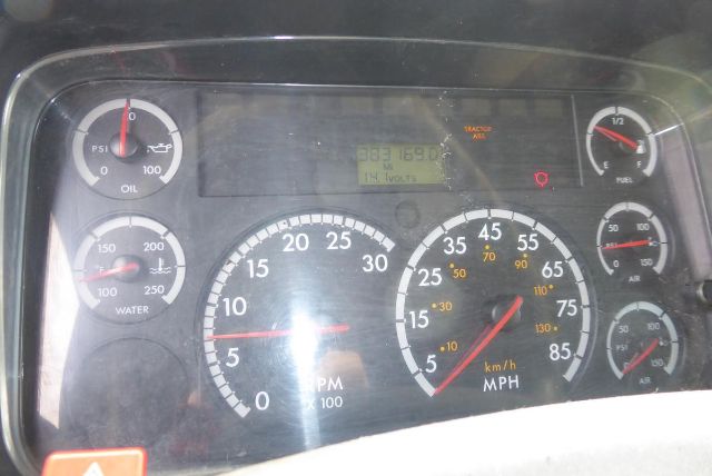 Dashboard of a Freightliner M2 106 showing gauges for oil pressure, water temperature, fuel, battery/air, and a central speedometer with mph; digital readout in the middle.