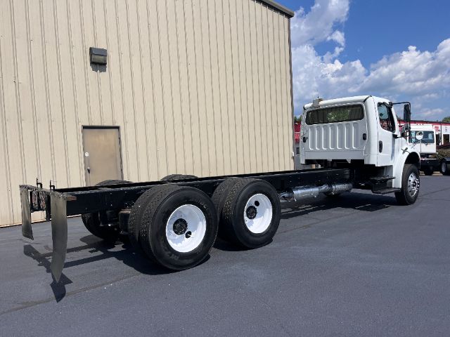 2015 Freightliner M2 cab and chassis truck with frameless chassis, three rear axles, white cab, black frame, and dual rear wheels.