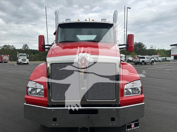 Front view of a red 2026 Kenworth T880 conventional daycab truck showing large chrome grille, Kenworth emblem, rectangular headlights, and bumper.