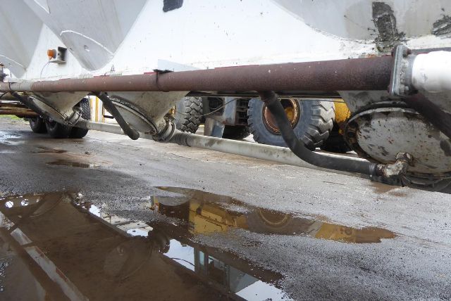 Fruehauf dry bulk trailer undercarriage showing steel piping and support beam with puddle on ground.
