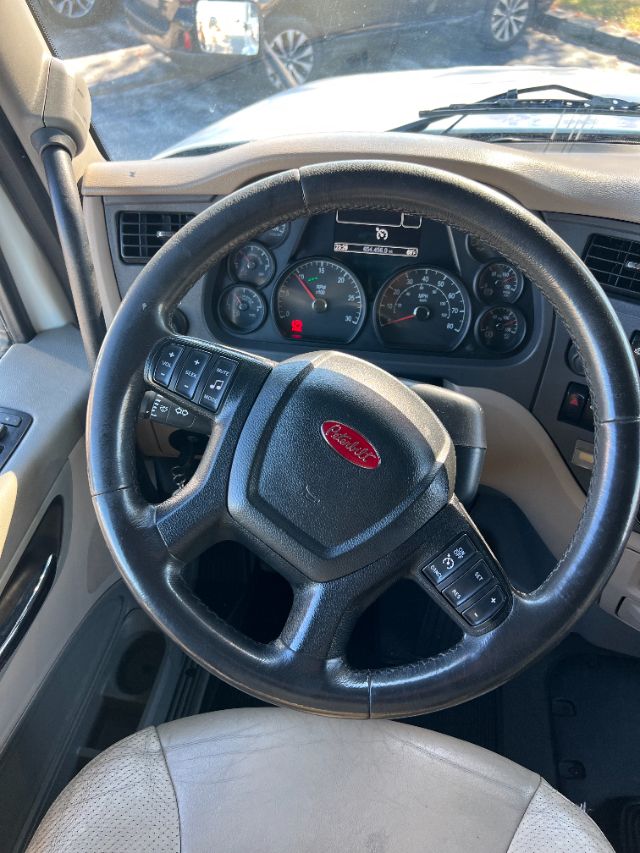 Peterbilt truck interior showing steering wheel with Peterbilt emblem, dashboard gauges, and steering column controls.