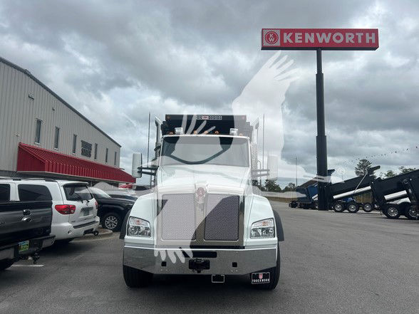 Kenworth T880 dump truck front view with Kenworth sign in background.