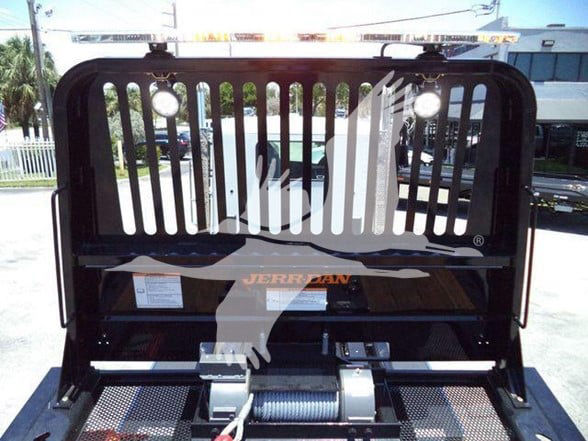 Kenworth T880 truck bed with a black metal headache rack and a Visible Jerr-Dan logo and mounting hardware; winch drum and roller fairlead visible.