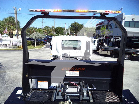 Isuzu FTR truck rear view showing hydraulic and hitch components, with a white cab in the background and an orange warning light bar on top.