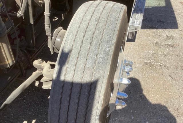Peterbilt 579 front wheel and dual rear drive hub showing tread-worn tire and chrome lug nuts.