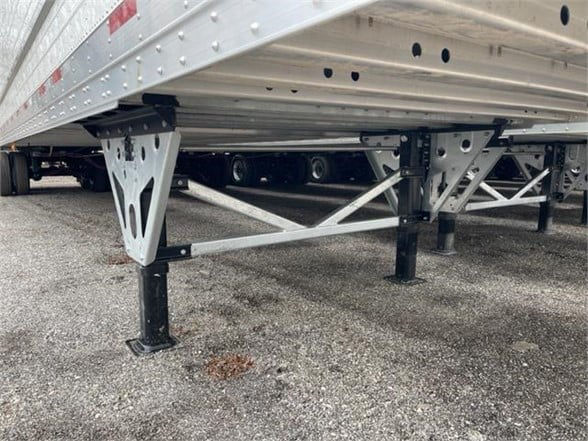 Reefer trailer undercarriage with adjustable legs and cross-braced frame showing aluminum side rails.