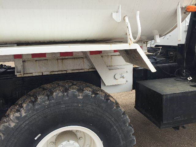 Truck rear wheel area of a 1986 American General M923A1 water tanker showing wheel, undercarriage, and tanker body.