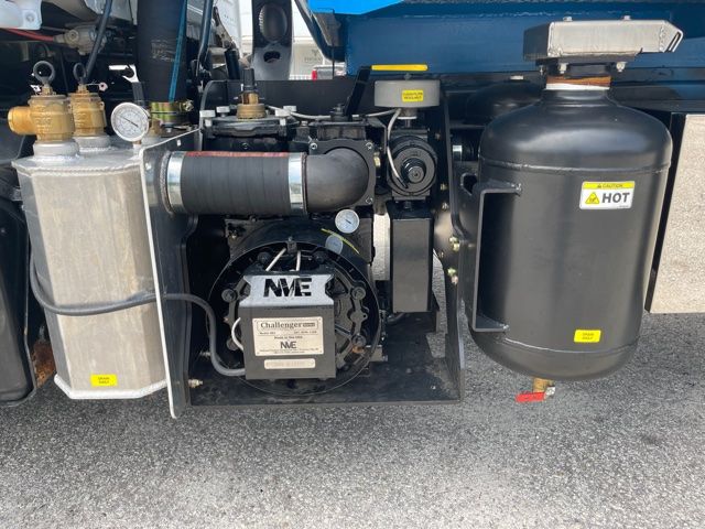 Truck side view showing front engine bay with coolant reservoir, air filter canister, hose, gauges, and compact metal components.