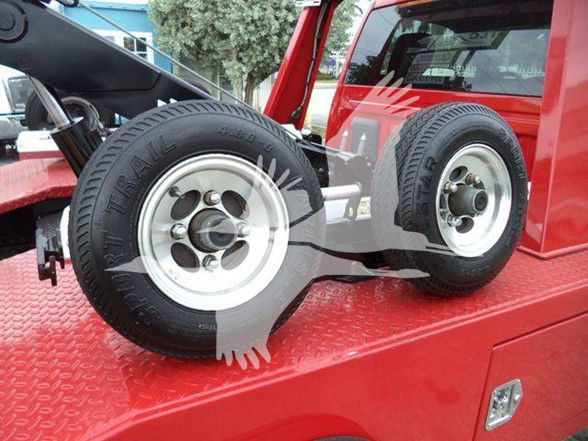 Two wheels of a red Ram truck on a flatbed exhibit. Visible tire sidewall reads 'RADIAL TIRE' and 'P275/70R18' with alloy wheels. Parts of truck bed and cabin in background.