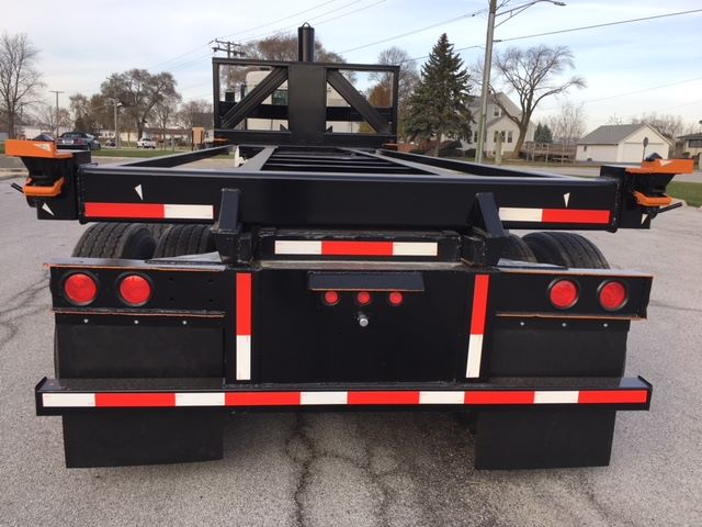 Rear view of a black 2003 Wabash tipper trailer with red and white reflective tape, dual rear axles, and a raised frame structure.