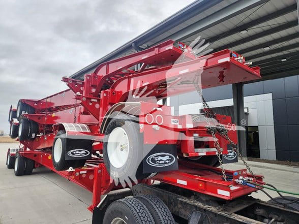 Red Cheetah trailer frame with wheels and hydraulic components, showing stacked trailer arms and chain safety latches.