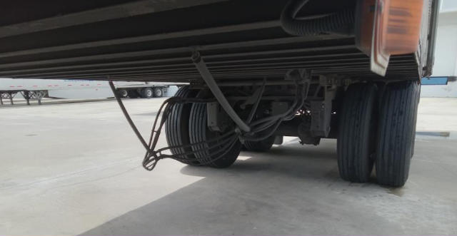 Trailer undercarriage showing electrical/reel assembly and dual wheels.