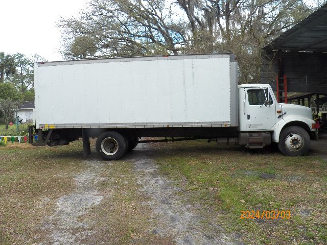 Box truck from IC Corporation 4700 model, white cargo box on chassis, side view.