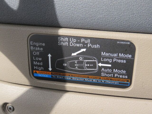 Dashboard label showing gear shift instructions and mode prompts inside a Freightliner Cascadia Evolution cab.