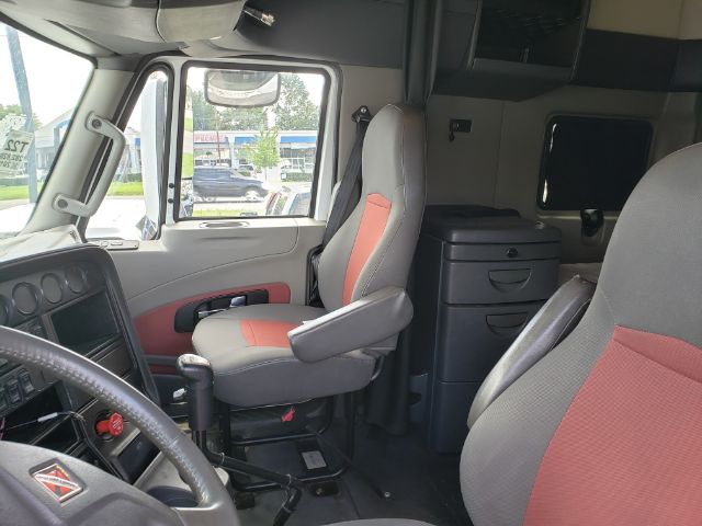 Interior of a 2015 International PROSTAR truck cab showing driver seat, steering wheel, and sleeper area with storage drawers.