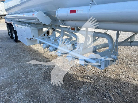 Trailer showing rear crossbar and bottom trough system of a Heil 9200 gallon tank trailer with piping, valves, and support structures visible.