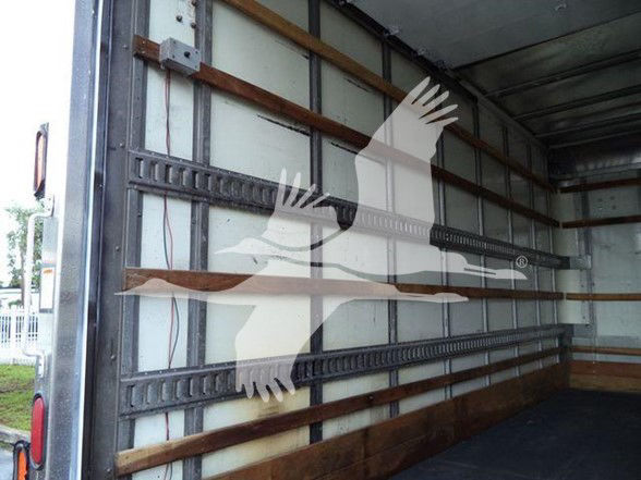 Inside cargo area of a box truck with wooden and metal wall rails; faint watermark overlay across image; no legible labels visible.