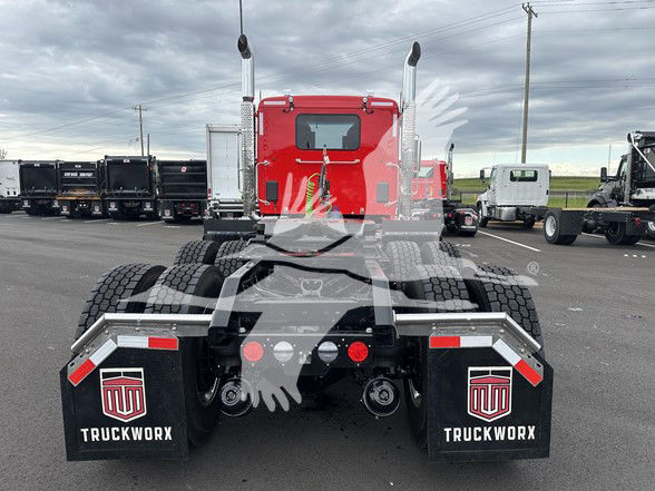 Kenworth T880 rear view showing dual rear axles, red cab, mud flaps with TruckWorx logo, and fifth wheel/tractor connections.