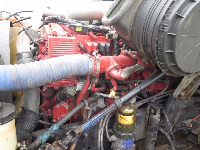 Truck engine bay of a 2010 International Prostar showing red engine, hoses, filter canister, and various components.