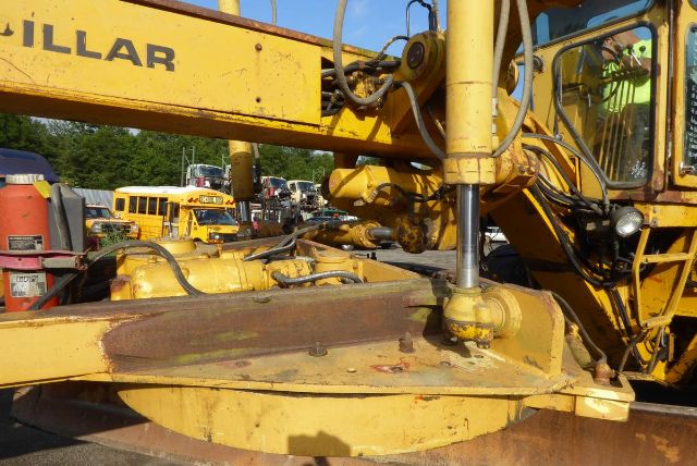Caterpillar 16G motor grader with hydraulic arm and circle blade area visible, yellow paint, hydraulic ram and engine components in view.