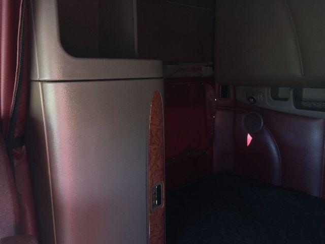 Interior of a 2012 Peterbilt 578 cab showing a wood-grain trim panel and leather seat with a maroon color scheme.