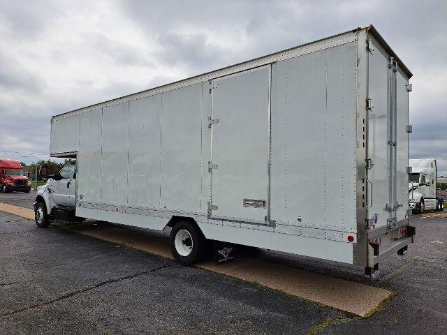 Moving van truck side and rear view showing large enclosed box with white paint and doors.