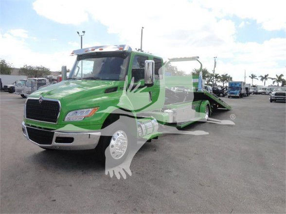 Green International MV tow truck with front grille, side mirror, and a flatbed winch area visible. Vehicle shows stock number MV607STEPSIDEFM in listing context.