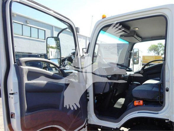 Isuzu NPR HD truck interior showing driver and passenger seats with open cab door; steering wheel, dashboard, and front seats visible.