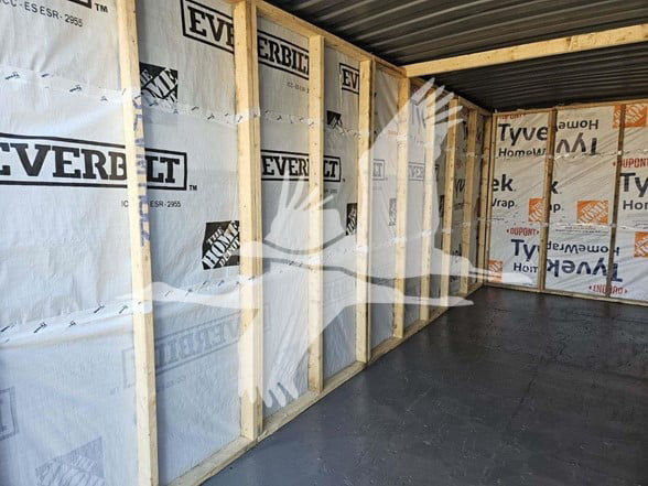 Container trailer interior under construction showing wooden studs and insulation with Everbilt branding.