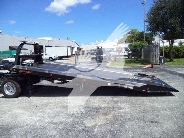 Tow truck trailer with a black flatbed. Visible text includes 'SUPER' on the ramp and 'MAGNUM' near the wheel area. No other legible labels or serials visible.