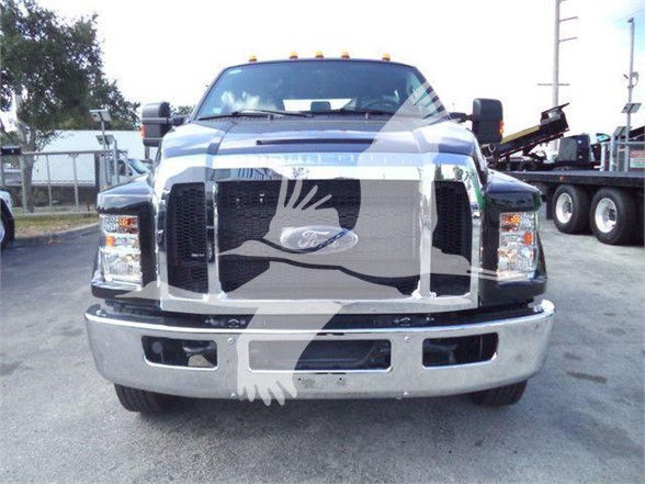 Front view of a new Ford F-750 XLT tow truck with large chrome grille, emblem in center, bumper, and dual headlights.