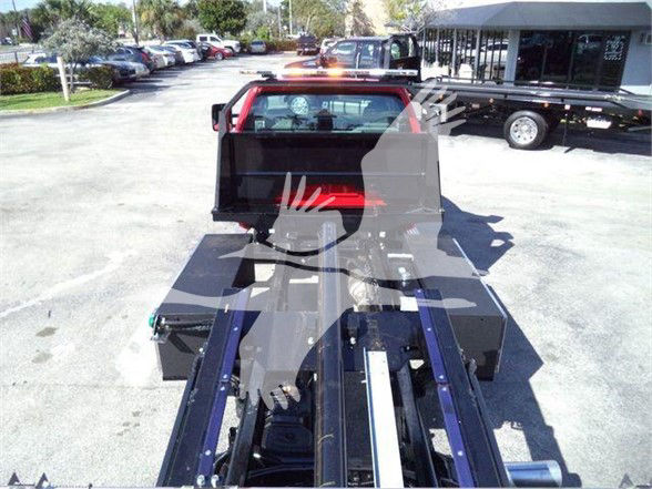 Truck bed of a 2023 Chevrolet Silverado 6500HD with a loading system and hydraulic components visible in the cargo area.