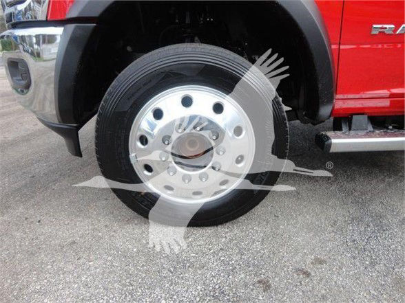 Ram 5500 front wheel and tire showing chrome hubcap and black tire with red body panel of truck.