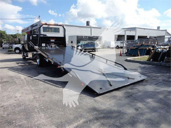 International MV tow truck with a flatbed ramp extended, rearview showing loading deck and wheel-lift area.