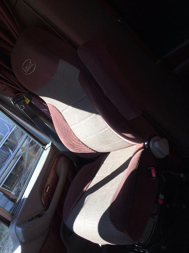 Peterbilt truck interior seat area with maroon upholstery, steering wheel, and door trim. Visible badge on seat headrest and window controls.