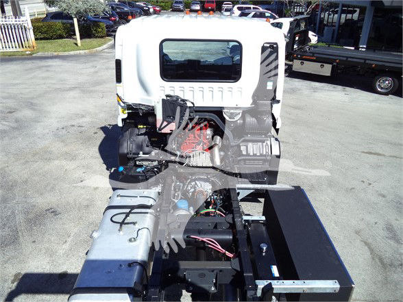 Isuzu FTR cab in service area showing engine bay frame and wiring harness visible.