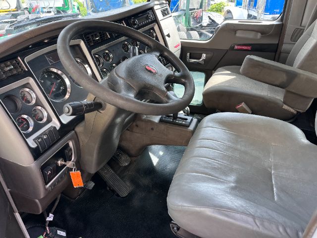 cab interior of a 2014 Kenworth T800 showing steering wheel, dashboard gauges, and driver seat in view.