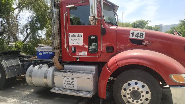 Peterbilt 386 conventional daycab truck with red cab, number 148 on fender, side sticker reads 'Trans International Trucking Inc.'
