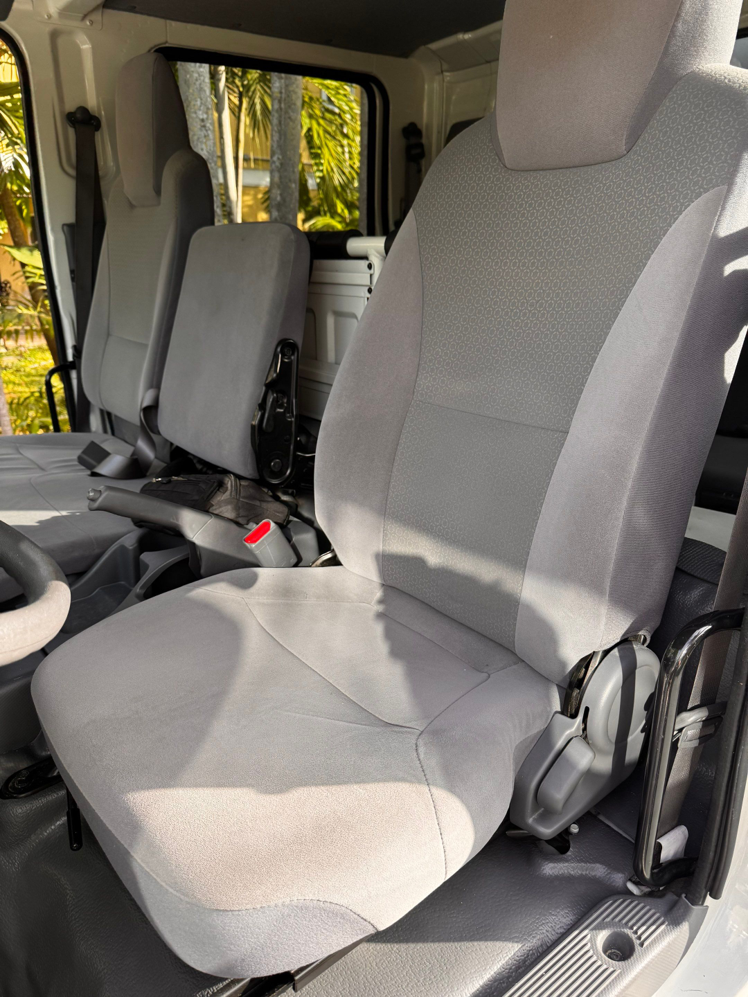 Isuzu NQR cab interior showing driver seat and passenger seat with grey fabric upholstery and visible seat adjustments.